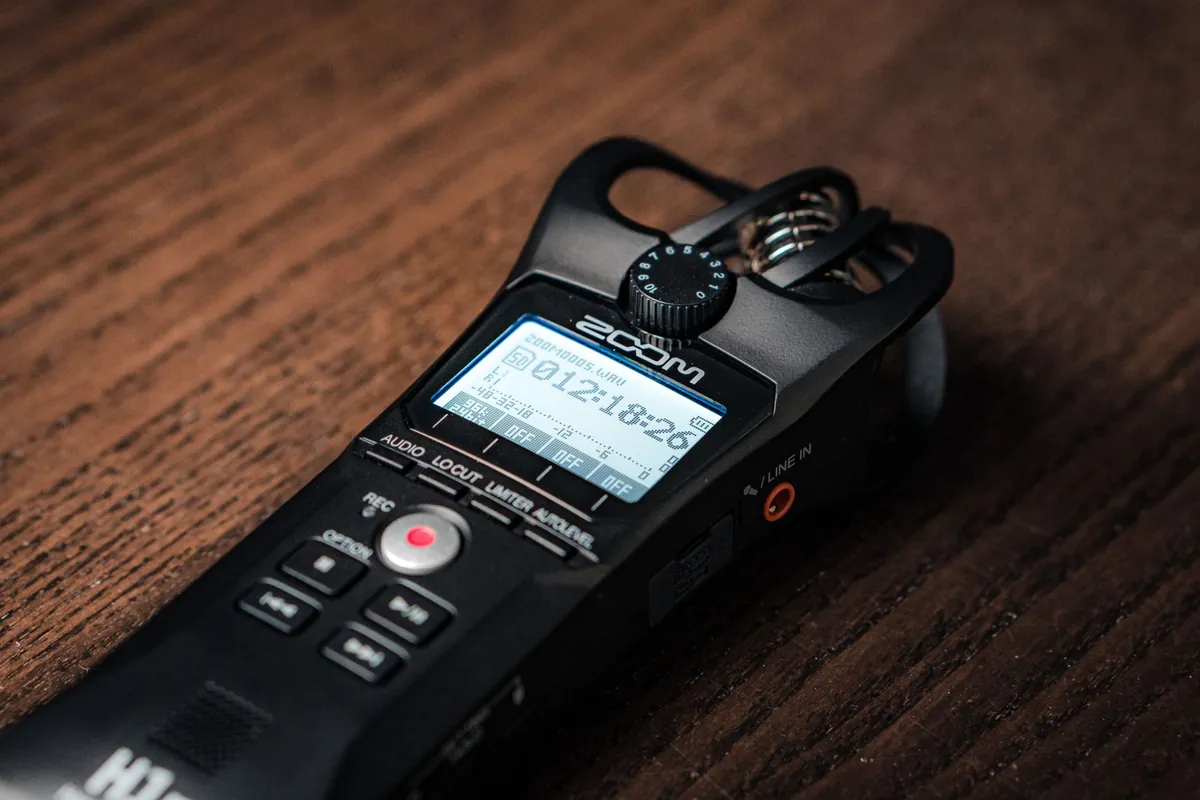 Handheld Zoom digital audio recorder lying on a wooden desk