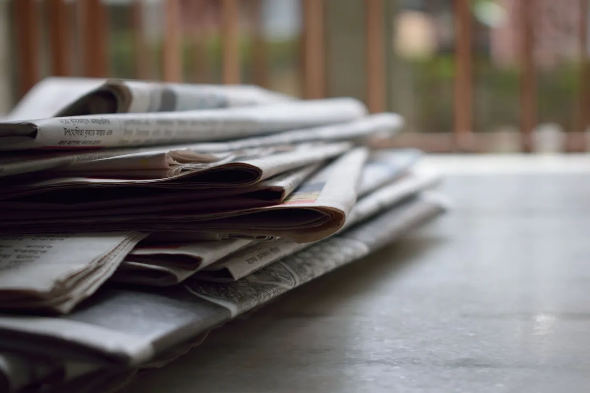 A loose stack of folded newspapers on a table