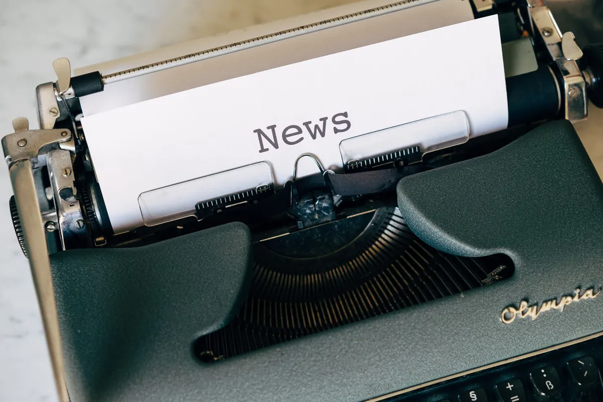 Vintage Olympia typewriter with a sheet of paper that reads News